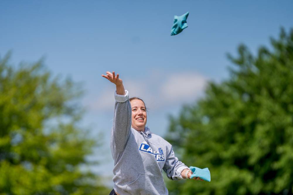 A player throws a bag and and watches it fly through the sky